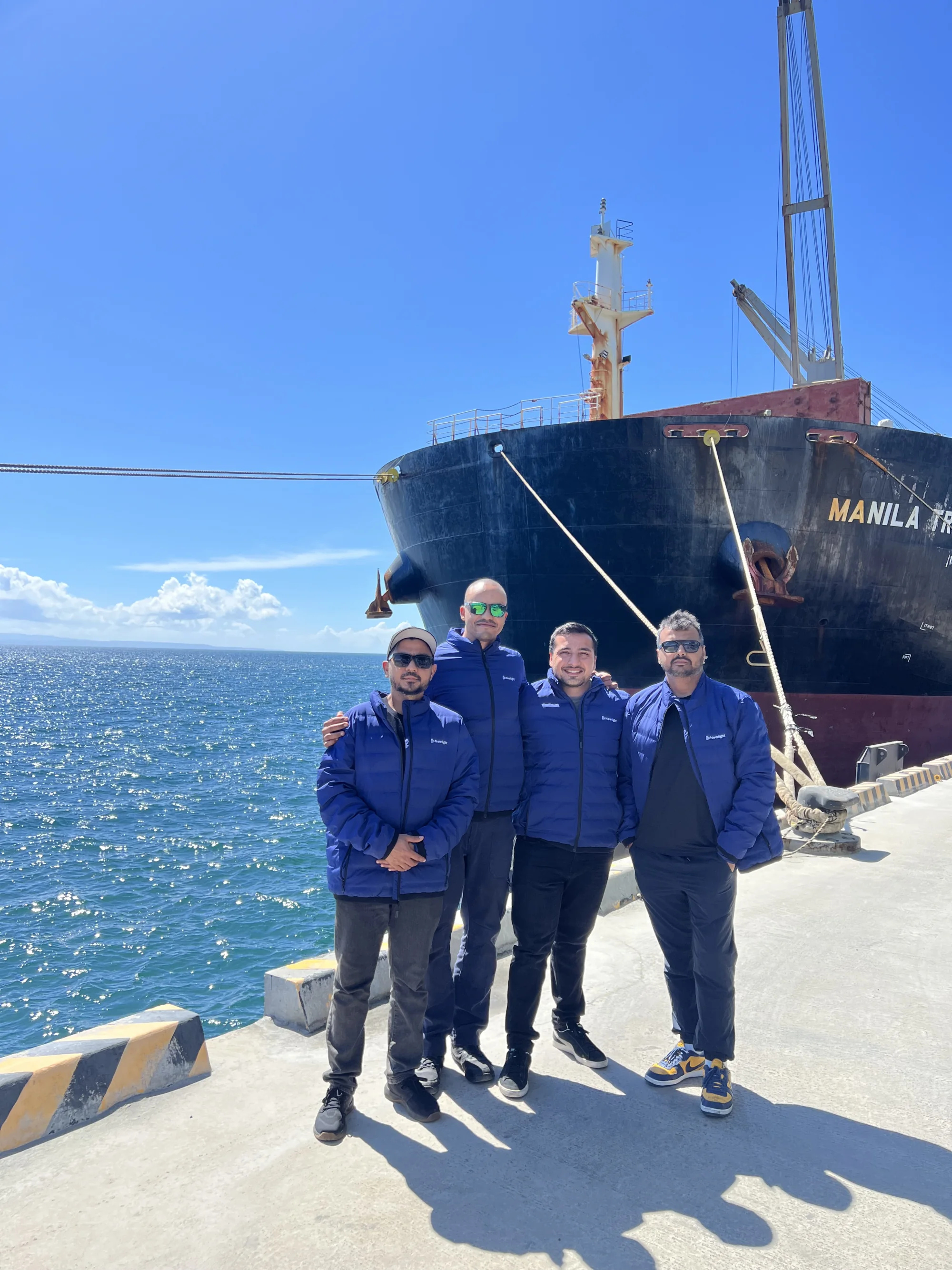Newlight team standing in front of a commercial cargo vessel